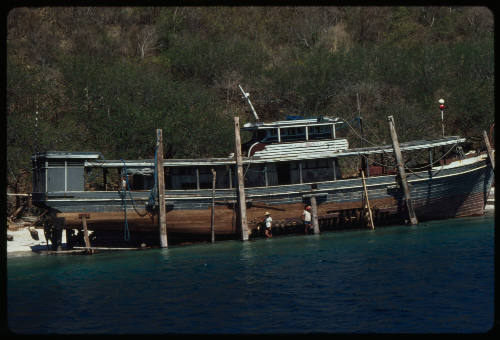 Wooden vessel on supports above water near beach