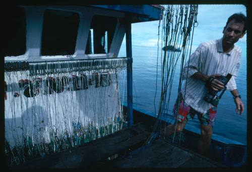 A person with a video camera on board a fishing vessel out at sea