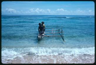 Two men on an outrigger canoe at beach