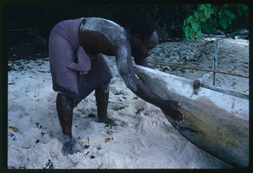 Man at end of outrigger canoe