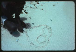 Man drawing symbol on sand