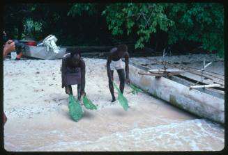 Two men placing leaves on beach