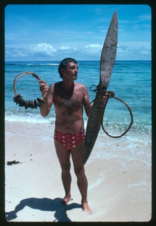 Ron Taylor holding up shark calling equipment at beach