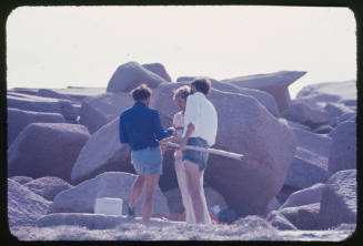 Three men standing in front of many large rocks