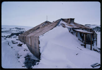 A wooden hut half buried in snow