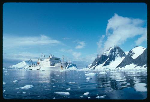 White vessel in the water near snow covered land