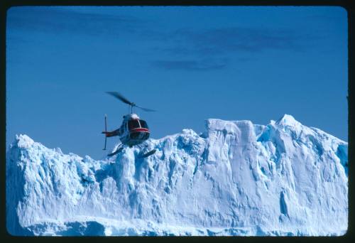 A helicopter in the air near ice shelf