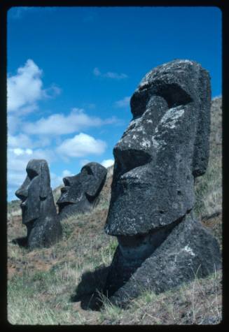 Three moai on a sloped grass surface