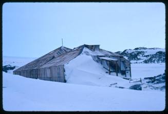 A wooden building partially covered in snow