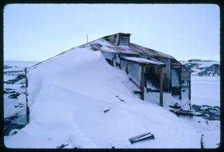 Outer wall of a wooden building partially covered in snow