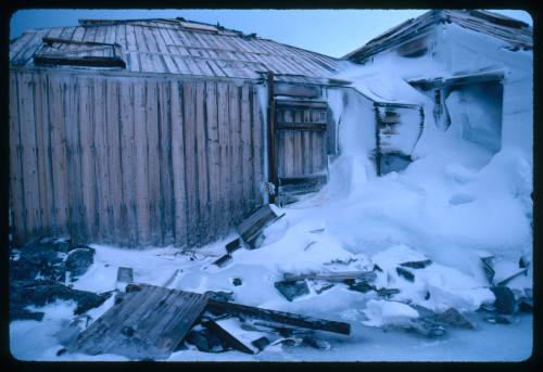 Wooden buildings partially covered in snow