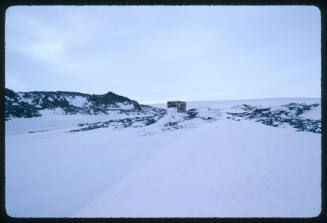 A wooden structure in the distance on snow covered surface