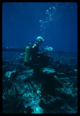 Diver seated on a bitt of a shipwreck
