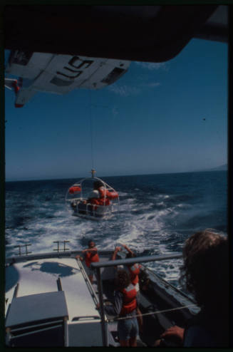 A United States Coast Guard helicopter hovering over a vessel out at sea