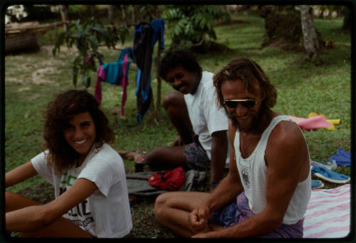 Three people seated on the grass possibly during filming of Blue Lagoon 2