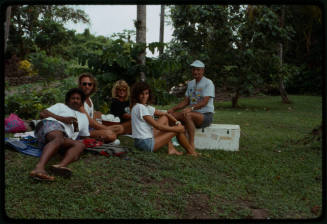 People seated on the grass possibly during filming of Blue Lagoon 2