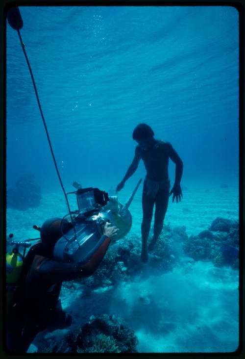 Diver with camera pointed at man and turtle underwater