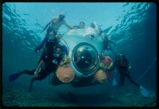 Group of divers posing underwater with a submersible