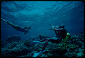 Diver filming a snorkeler swimming over a coral reef