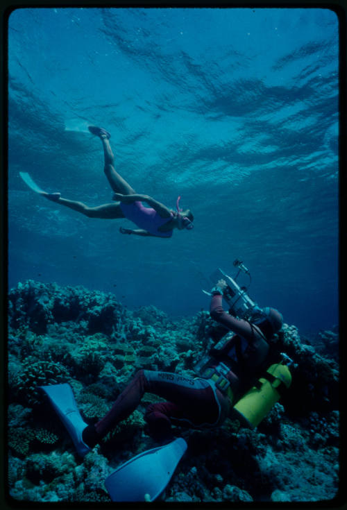 Diver filming a snorkeler swimming over a coral reef