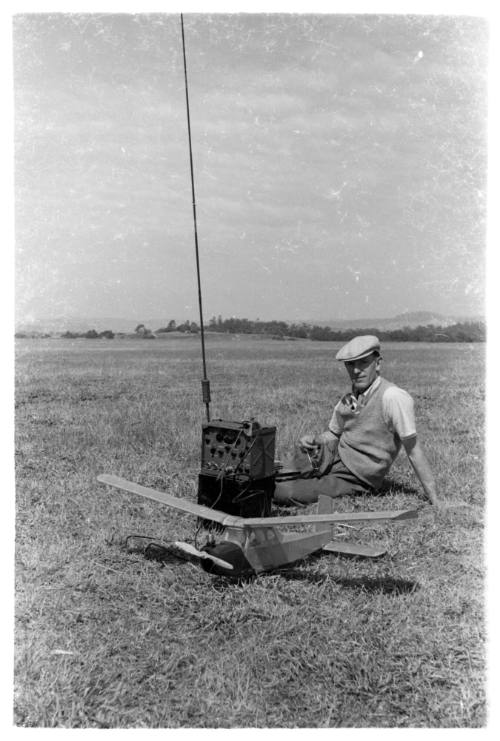 Len Spindler sitting on a grassy field behind a model plan