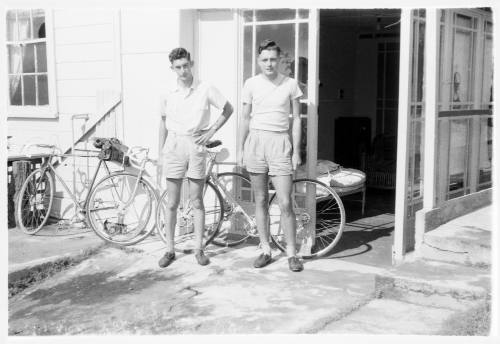 Two young men standing in front of bicycles