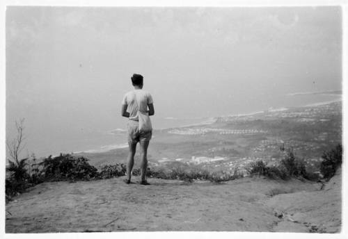 Man with a sling bag looking out over a coastal town