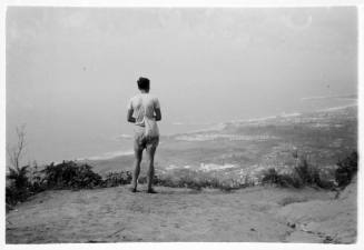 Man with a sling bag looking out over a coastal town