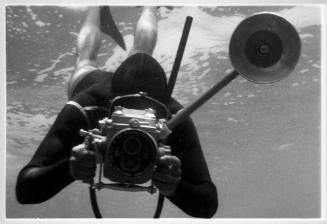 Black and white photo of a diver with an underwater camera rig