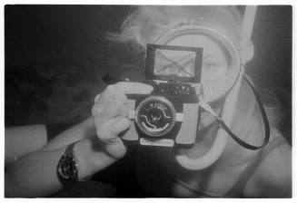 Black and white photo of Valerie Taylor holding an underwaer camera