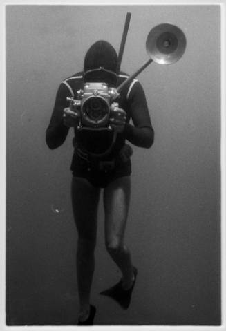 Black and white photo of diver holding an underwater camera rig