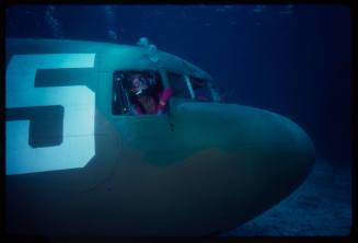 Valerie Taylor looking out the cock pit of a submerged prop plane from the filming of "Sky Pirates"