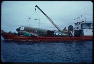 Prop plane being lowered into the ocean by a crane for the filming of "Sky Pirates"