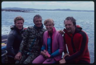 Ron and Valerie Taylor with two other people sitting in a boat in wetsuits