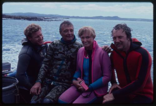 Ron and Valerie Taylor with two other people sitting in a boat in wetsuits