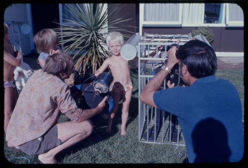 Child posing in front of a camera next to a mini shark cage prop