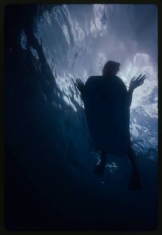 Underwater silhouette of a person with limbs splayed on a bodyboard