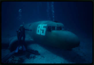 Valerie Taylor next to a submerged prop plane from the filming of "Sky Pirates"
