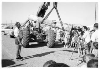 Man with a camera shooting through a cannon barrel hoisted by a crane