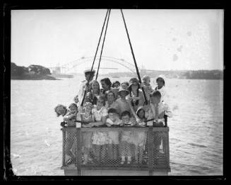 A group of children hoisted in a crate on board HMAS AUSTRALIA II