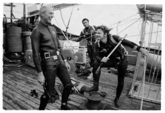 Shot of three divers in gear with spear rods on board a large vessel at sea. Images taken for documentary Blue Water, White Death.