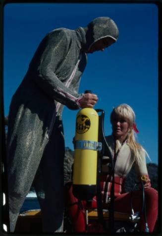 Behind the scenes image from the television feature, Operation Shark Bite, that documented Ron and Valerie Taylor testing the efficacy of the chainmail suit (mesh suit) against shark bites.  