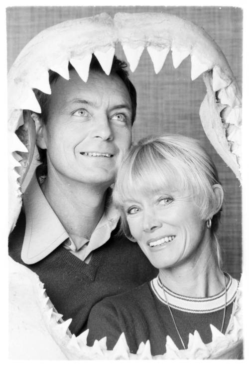 Black and white  Portrait shot of Ron and Valerie Taylor framed by a shark jaw