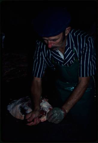 Butcher gutting fish using a mesh glove