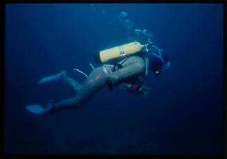 Underwater shot of Valerie Taylor in full mesh suit holding an underwater camera