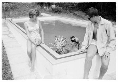 Shot of two people sitting at pool edge with Valerie Taylor in water holding up a large Crayfish