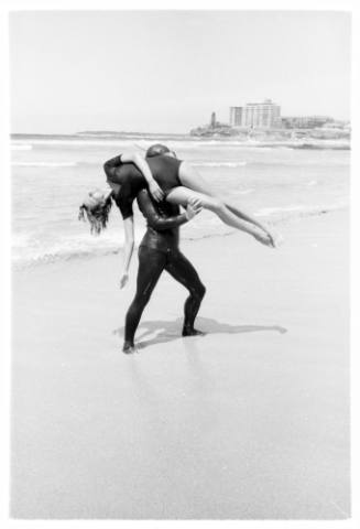 Shot of person held up over the shoulder of another standing at the shoreline of a beach