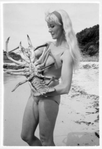 Shot of Valerie Taylor standing holding a large Crayfish