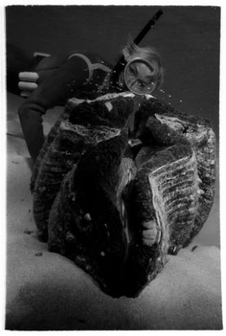 Underwater shot of freediver behind a Giant Clam on the seafloor