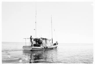 Shot of a yacht on calm sea with single person at stern with no sails up
